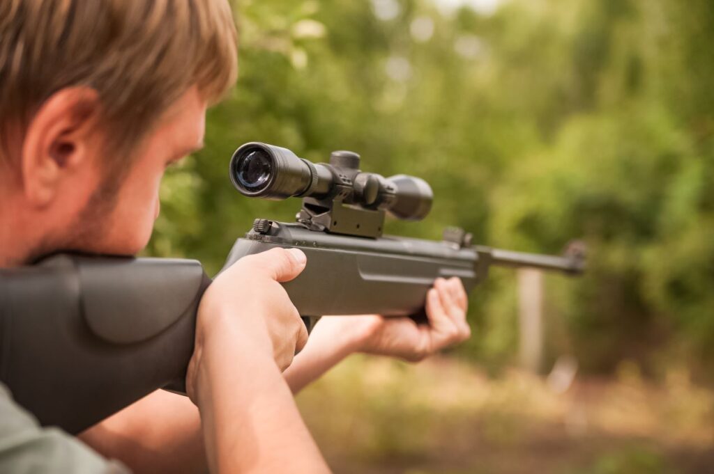 Mann zielt mit Luftgewehr, das mit Co2 Kapseln betrieben wird, im Freien auf ein Ziel