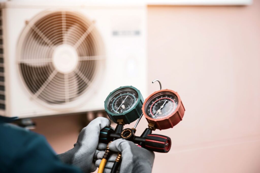 Technician holding a digital vacuum gauge set while checking pressure levels in an HVAC system