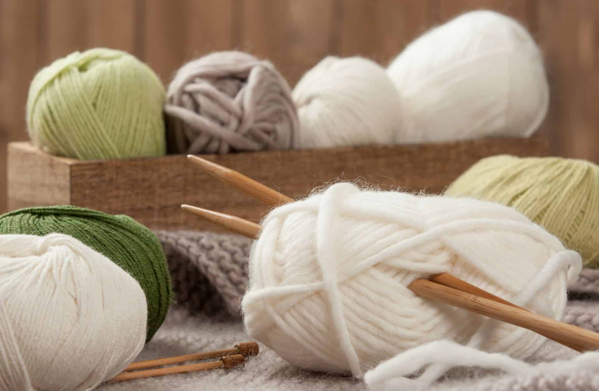 Wollknäuel in Naturfarben mit Stricknadeln aus Holz
