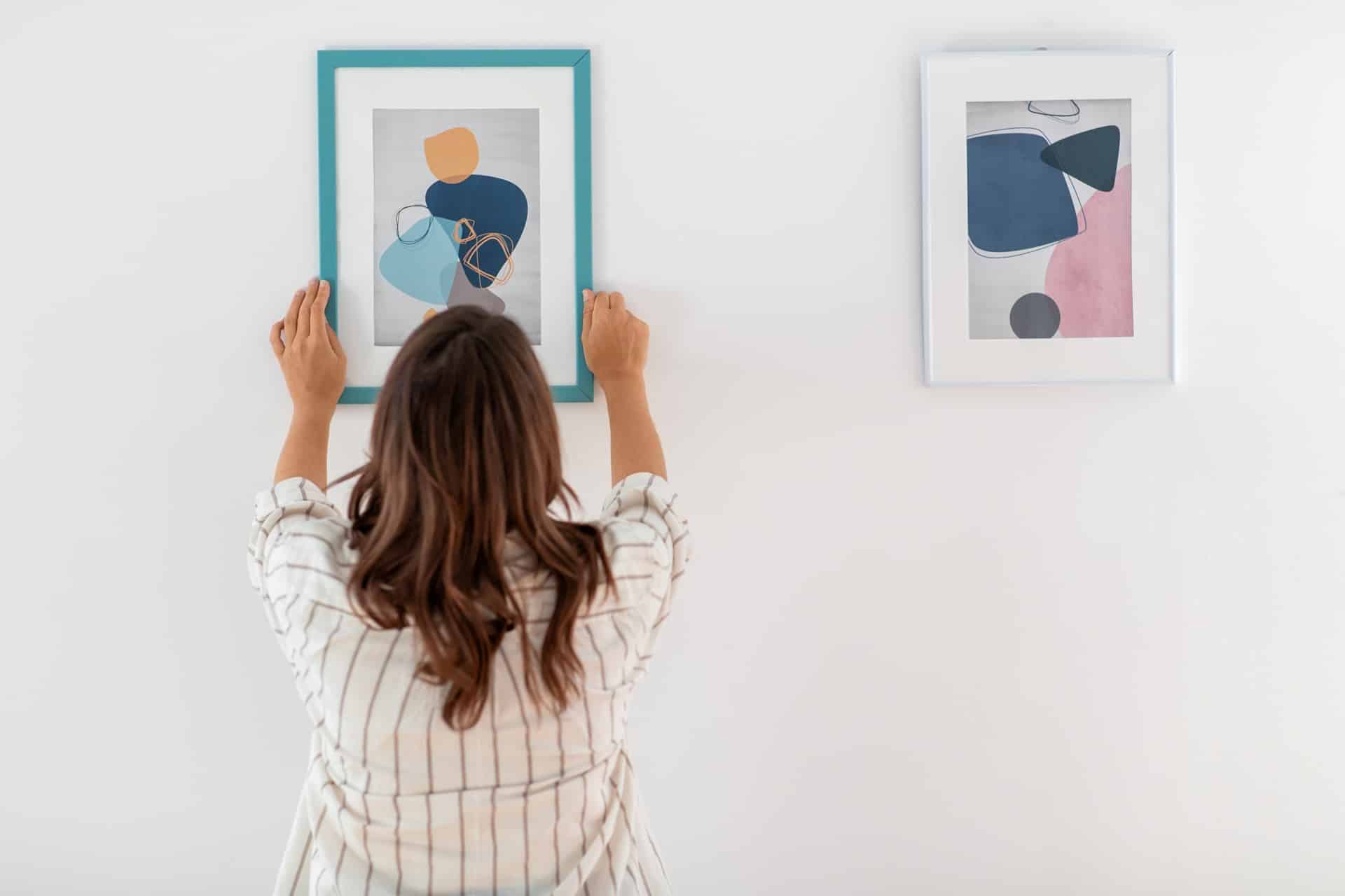 Frau hängt modernes Kunstbild an Wand | Katana